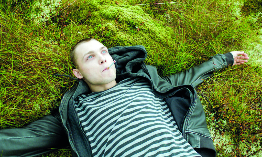 Der junge Robert liegt im Gras und raucht eine Zigarette.